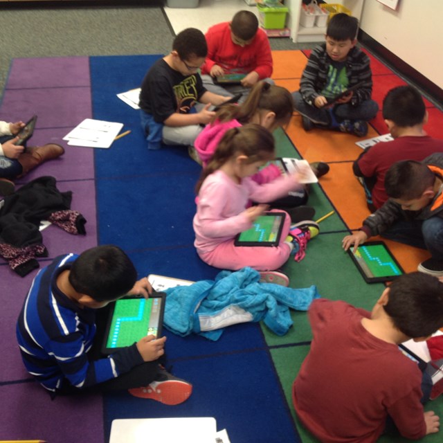 Students use tablets to practice computer coding.